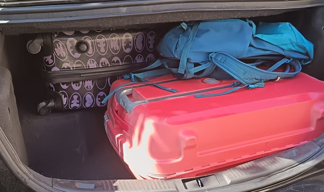 Coffre ouvert de la berline, chargé de deux valises et d'un sac à dos, avec de la place disponible