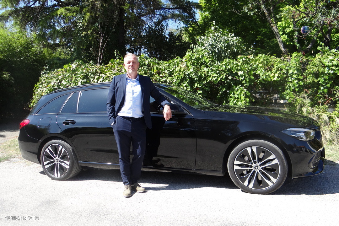 Yohann, chauffeur privé, appuyé à sa Mercedes Classe C break noire